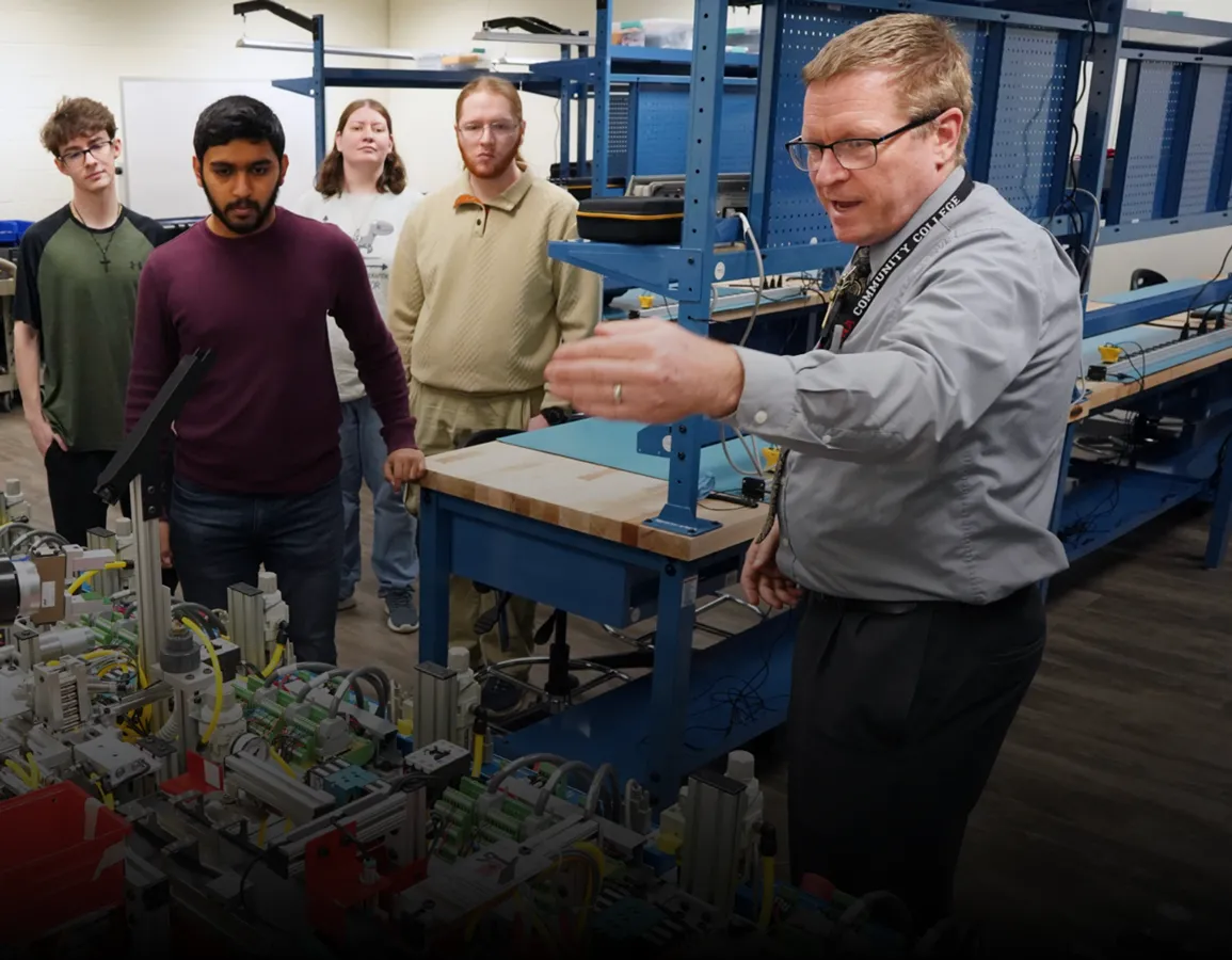 A faculty member explains the workings of a robot to Mechatronics students