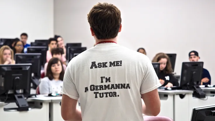 Germanna Tutor facing students with a t-shirt saying to "Ask Me!" 