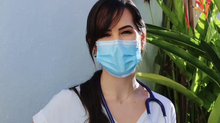 female nurse with mask sitting on bench outside