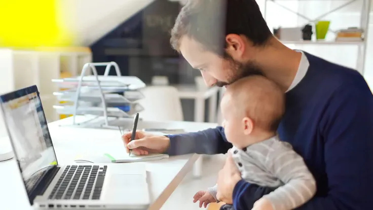Father student working on laptop holding baby